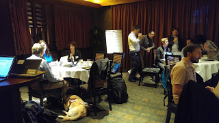 Four tables with 10 participants conferring and working at laptops